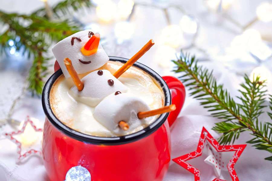 Red mug of hot chocolate with marshmallow snowman garnish and pine branches — Winter Drinks Wallpaper