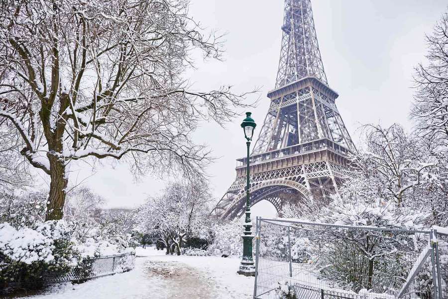 Snow-covered Eiffel Tower surrounded by bare trees and a fence on a winter day. — Winter Picture