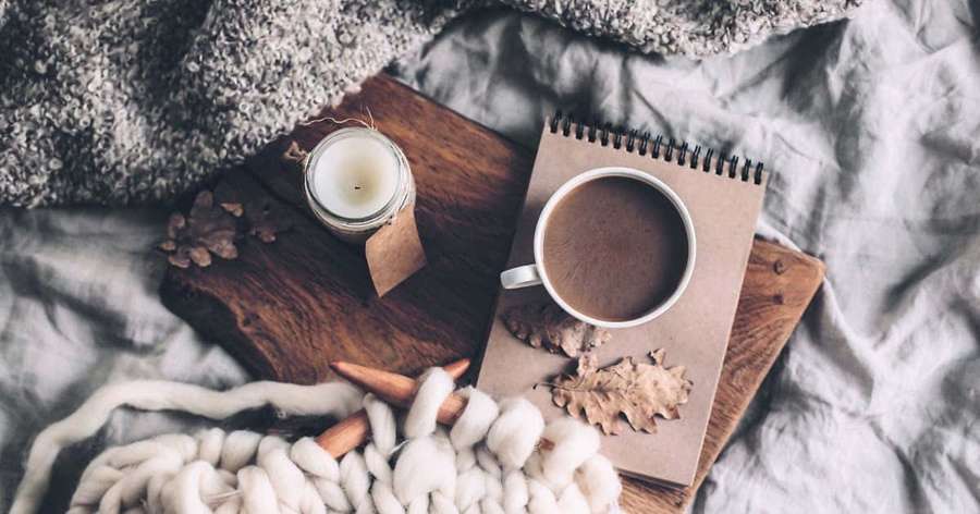 Gemütliches herbstliches Morgen-Setup mit Kaffeetasse, Notizbuch, Kerze und Wolldecke auf dem Bett. — Wintersaison Wallpaper