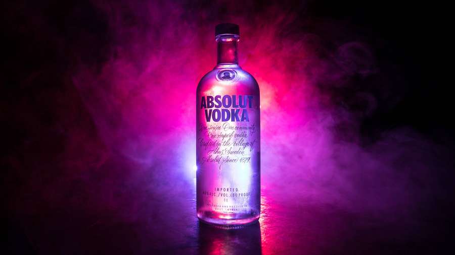 Absolut Vodka-Flasche, beleuchtet von Neonlichtern in rauchiger Dunkelheit. — Wodka Wallpaper