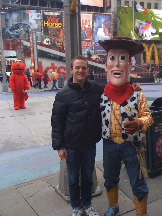 Mann posiert mit Woody- und Elmo-Maskottchen am Times Square. — Woody Bilder