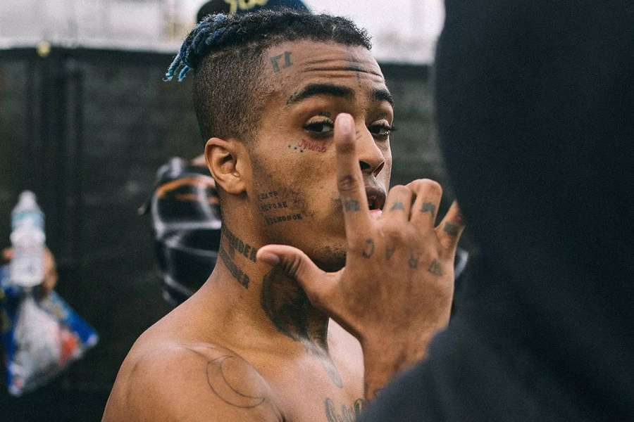 Tattooed man with blue dreadlocks making a hand gesture. — Xxxtentacion Computer Background
