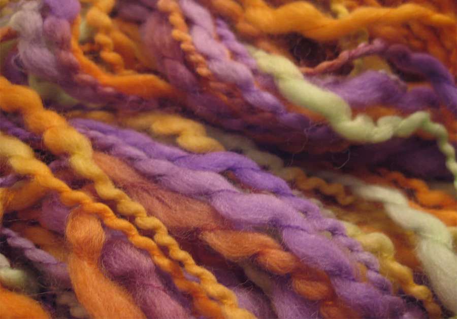 Nahaufnahme von bunten, gedrehten Garnsträngen in Lila, Orange und Hellgrün. — Yarn Wallpaper