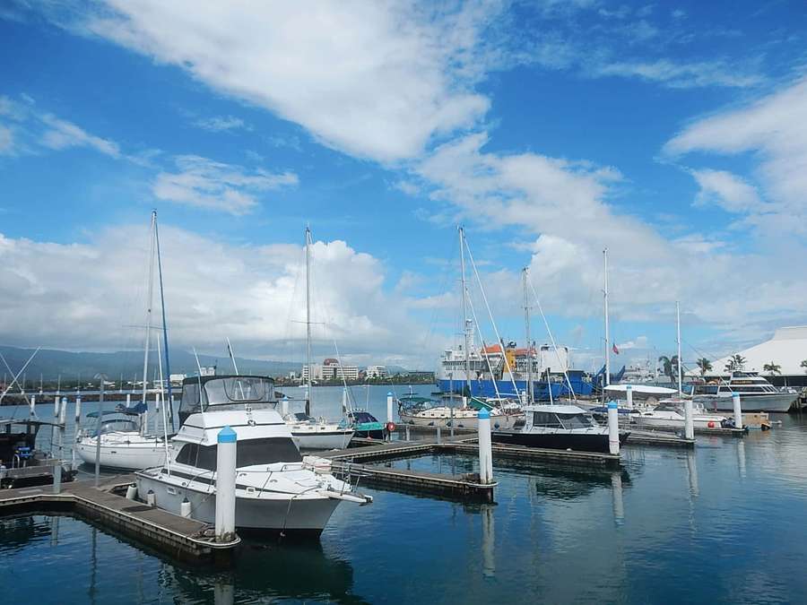 Barcos atracados en un puerto soleado con agua azul clara y nubes dispersas. — Yate Fondos de pantalla