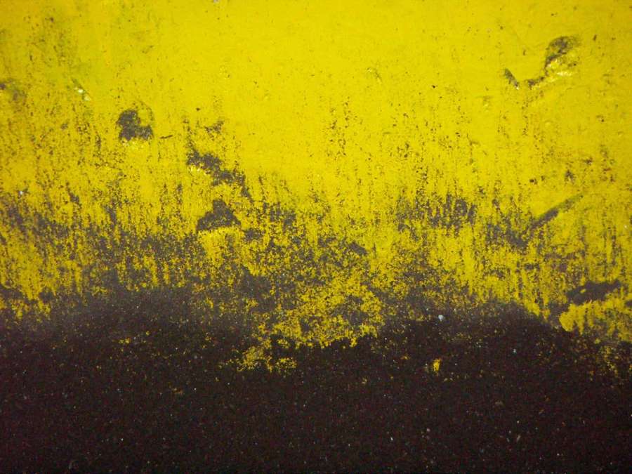 Abstract wall with bold yellow paint over dark textured surface — Yellow And Black Background
