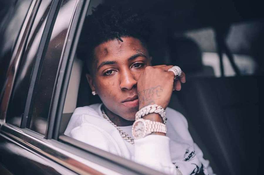 Young man in white hoodie and gold jewelry leaning out car window — Youngboy Picture