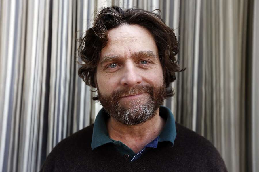 Man with beard and blue eyes smiling in front of striped curtain. — Zach Galifianakis Wallpaper