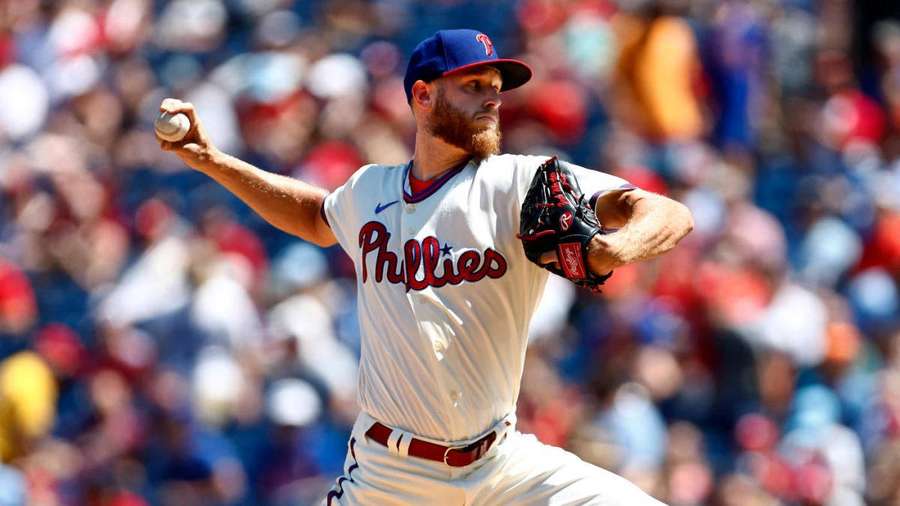 Lanciatore di baseball in uniforme bianca dei Phillies che lancia una palla durante una partita diurna. — Zack Wheeler Sfondi
