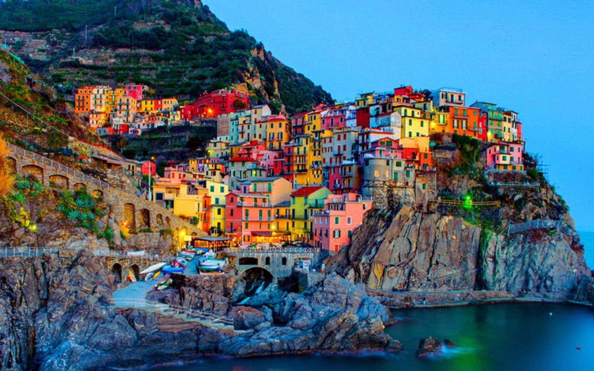 A Colorful Village On A Cliff Overlooking The Ocean Background