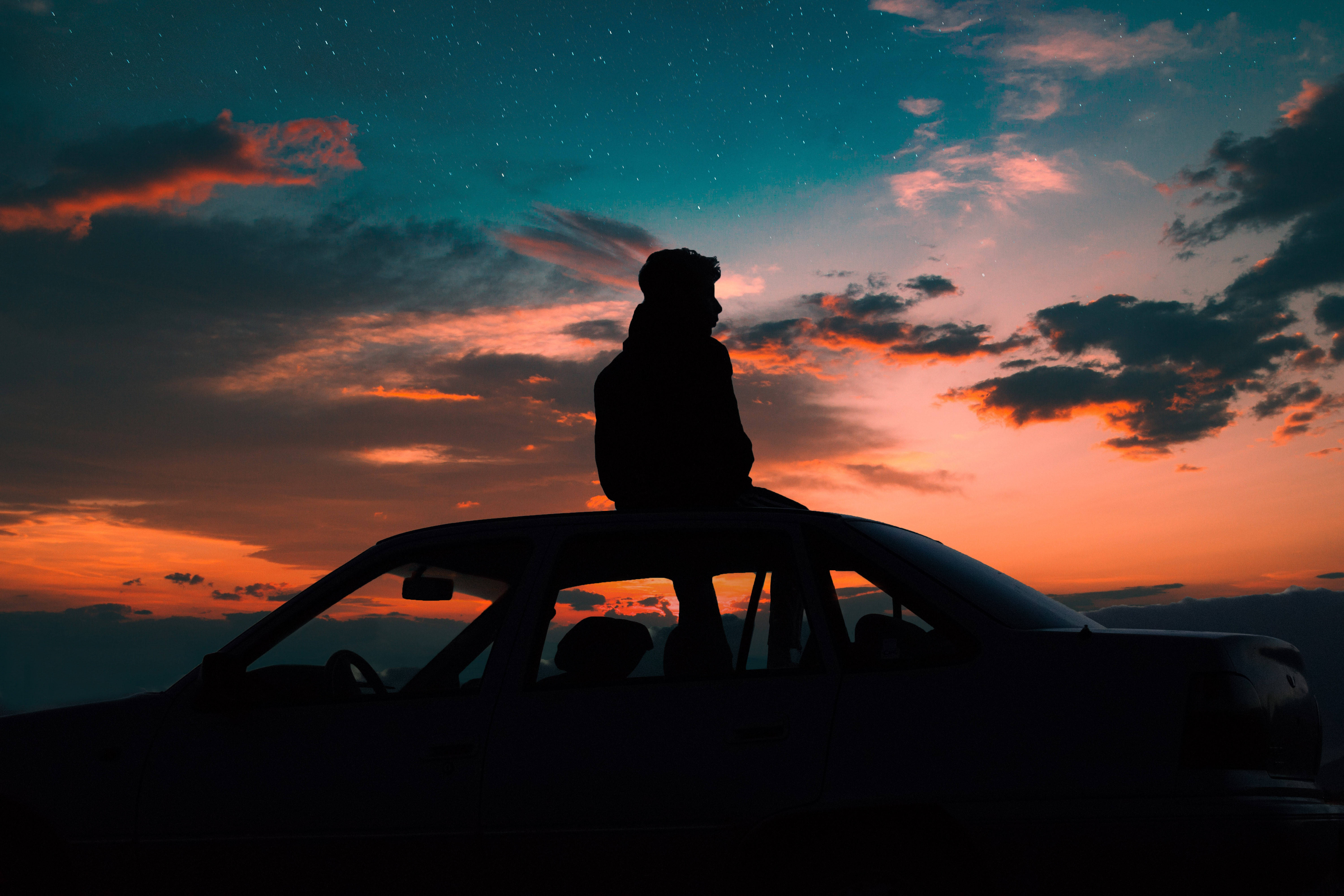 A Person Sitting On The Hood Of A Car Background