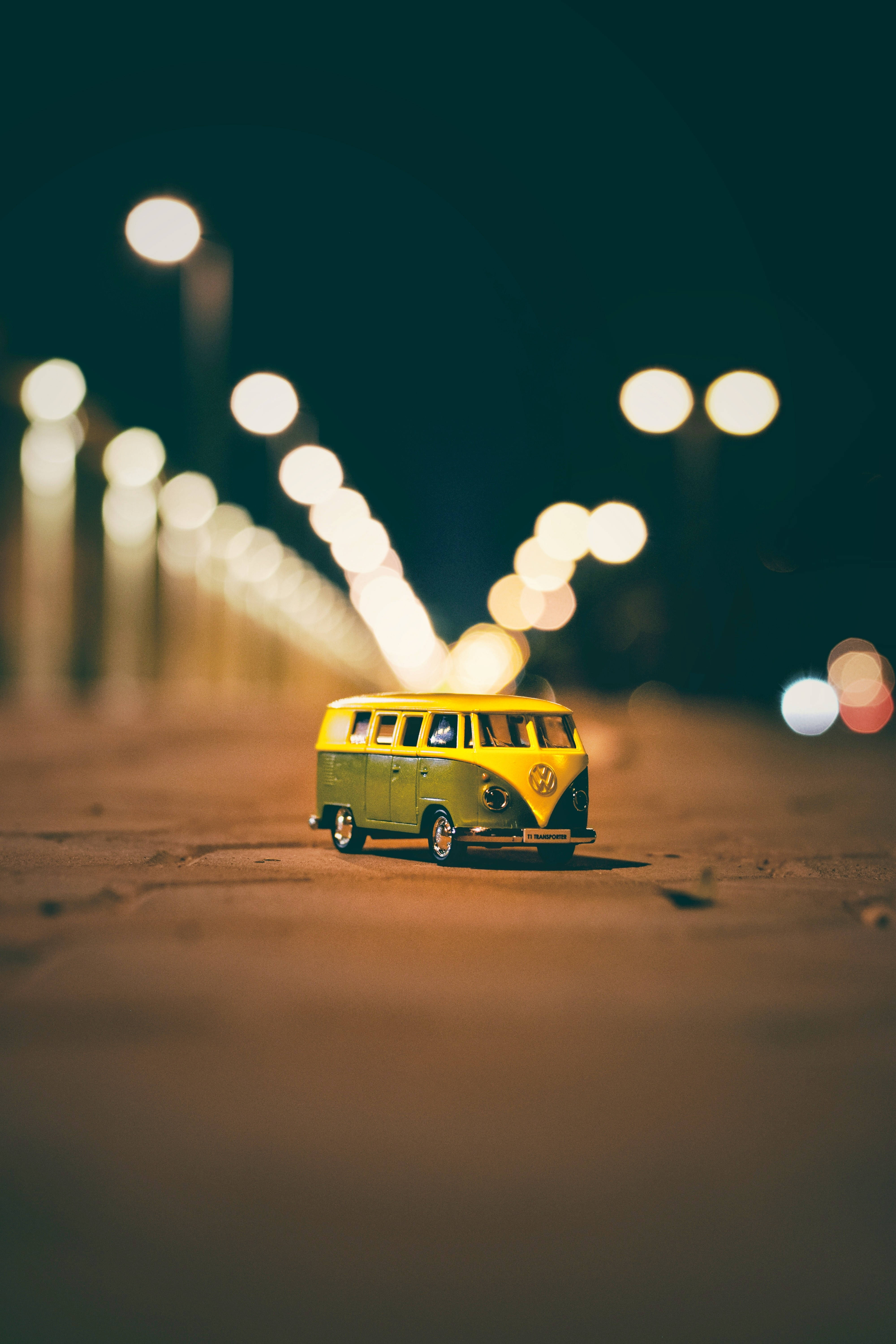 A Yellow And Green Toy Bus On A Street Background