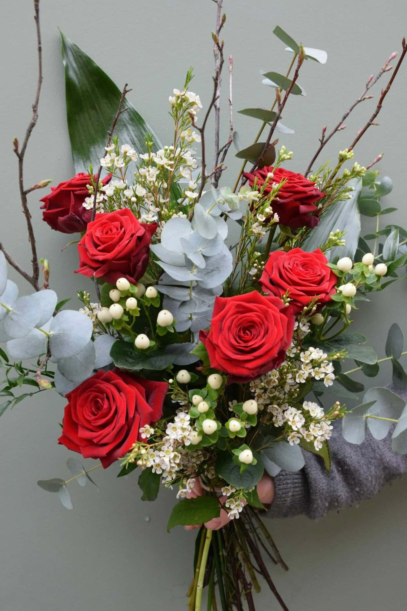 Download A Woman Holding A Bouquet Of Red Roses And Greenery