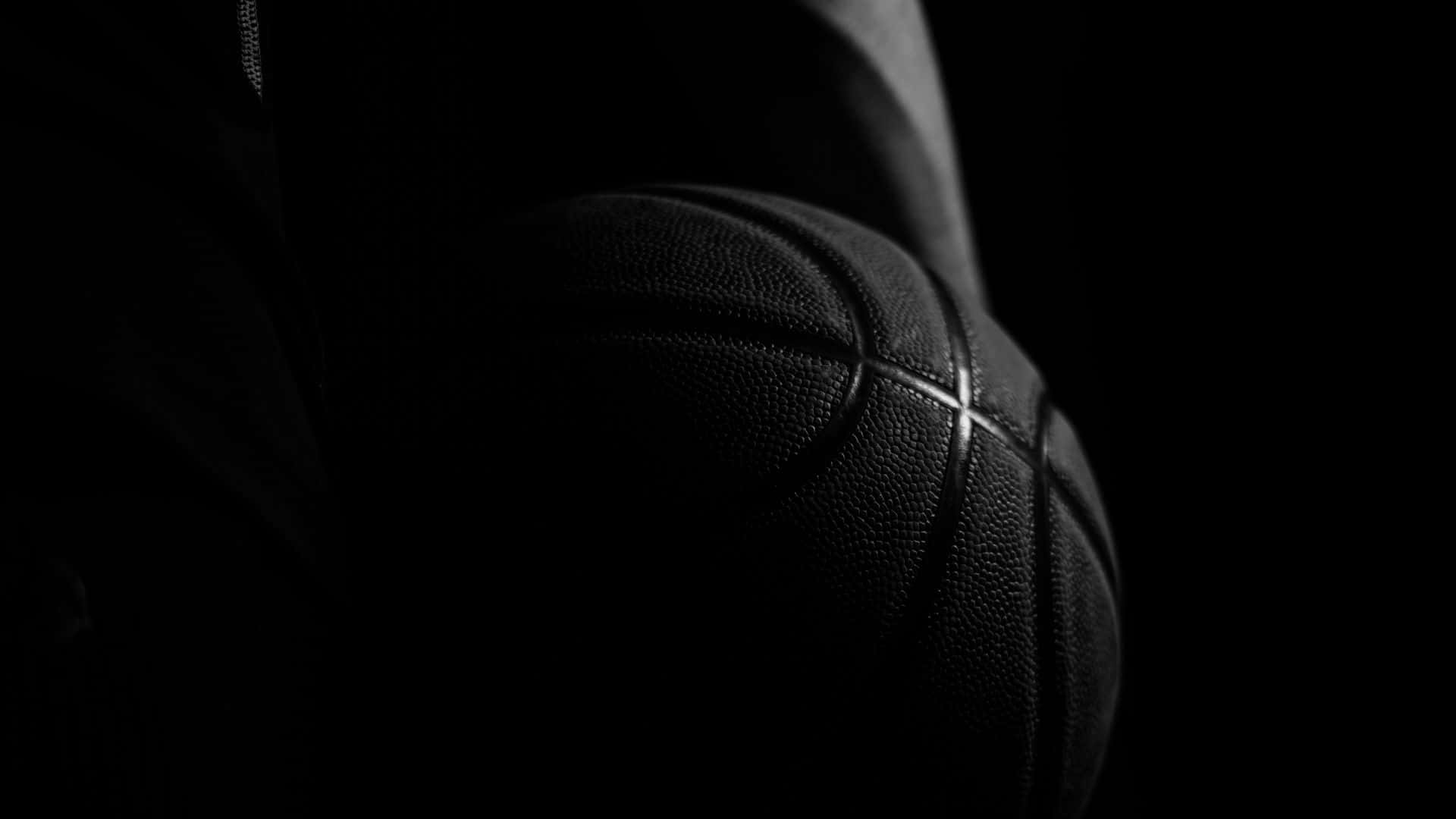 A Basketball Player Holding A Ball In The Dark