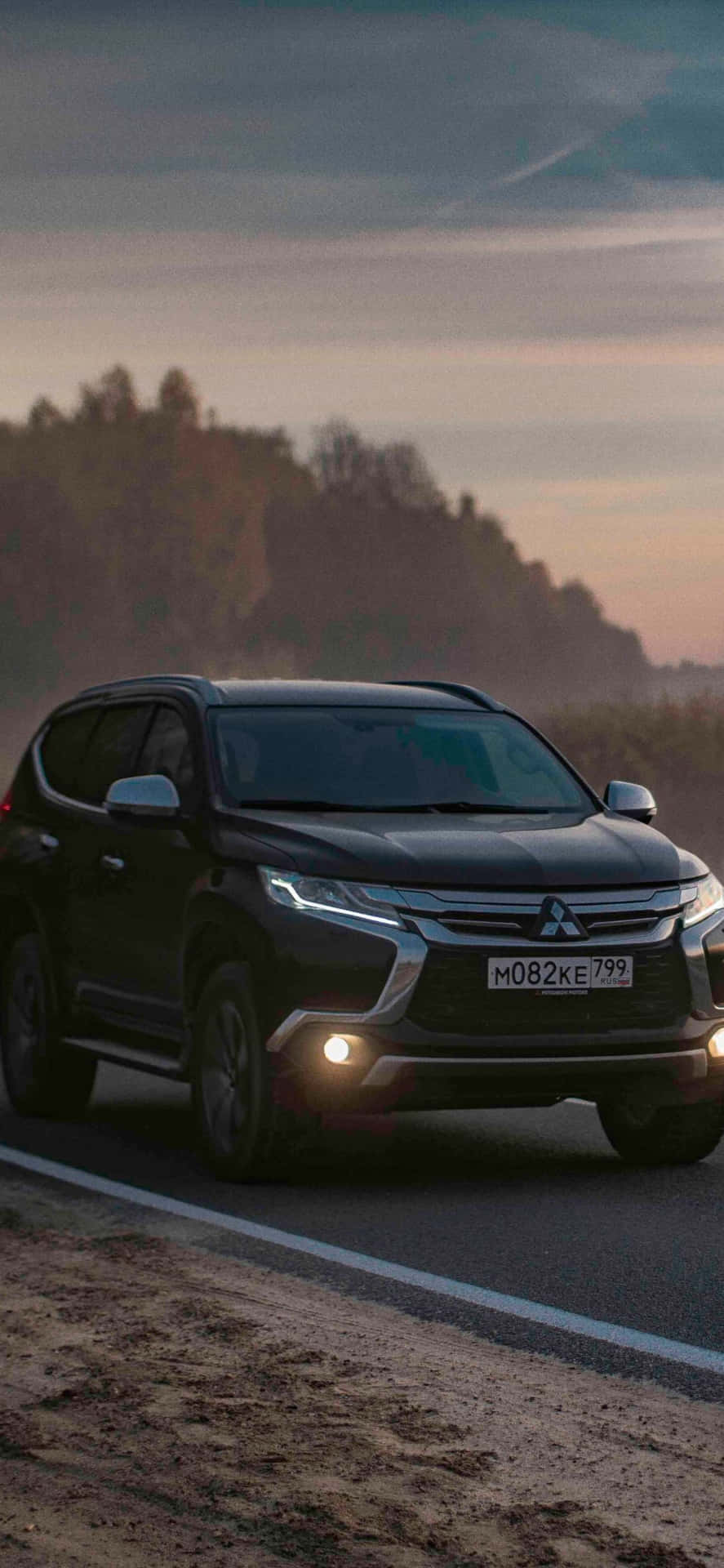 The 2019 Mitsubishi Outlander Is Driving Down A Country Road Wallpaper