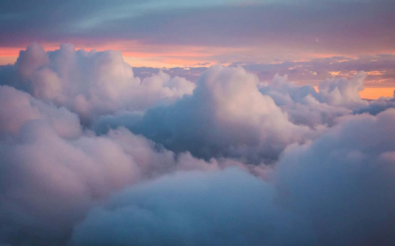 A View Of Clouds From An Airplane At Sunset Wallpaper