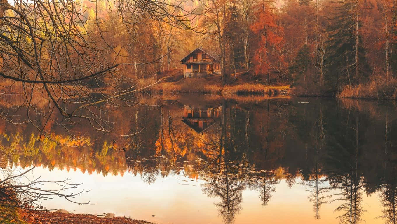 A House Is Reflected In A Lake In Autumn Wallpaper