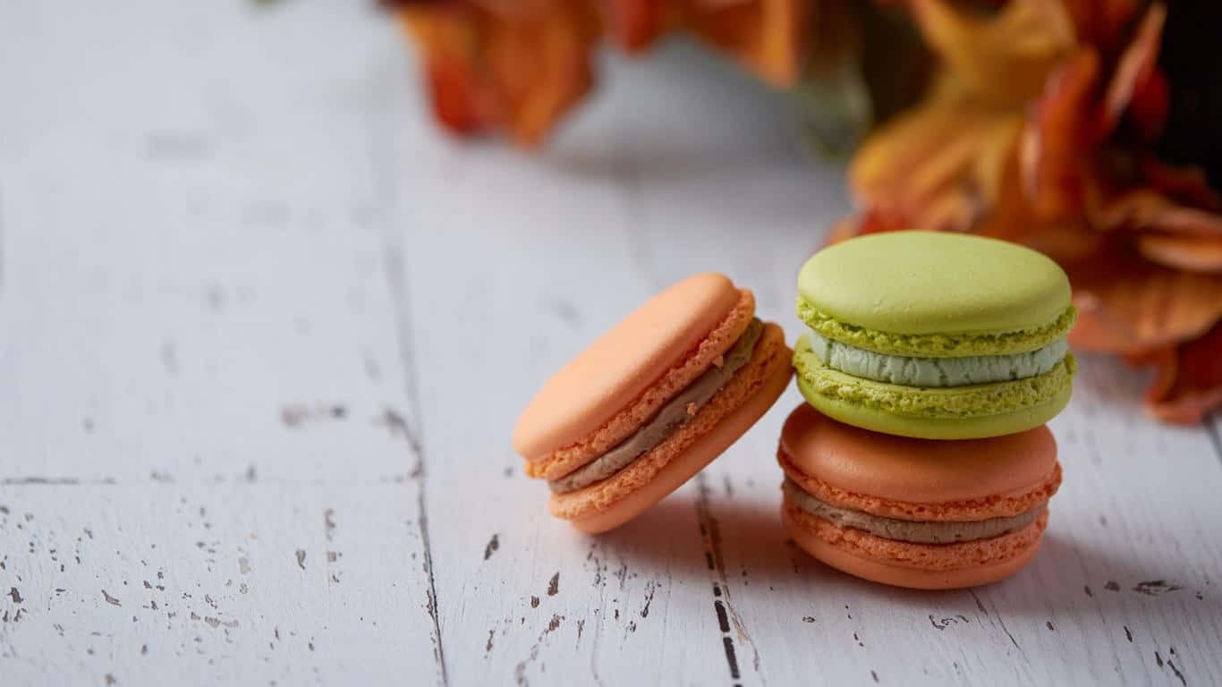 Three Macarons Sitting On A Wooden Table