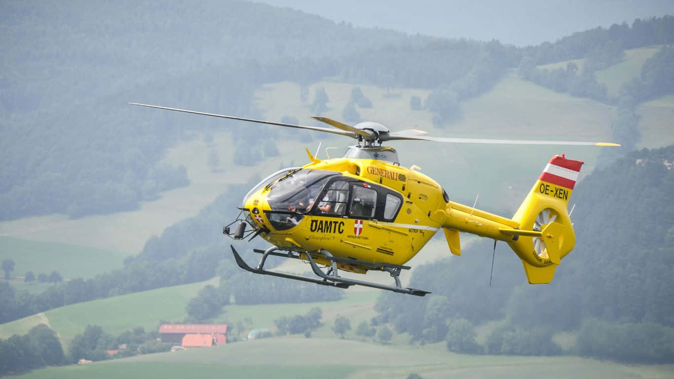 A Yellow Helicopter Flying Over A Mountain Range