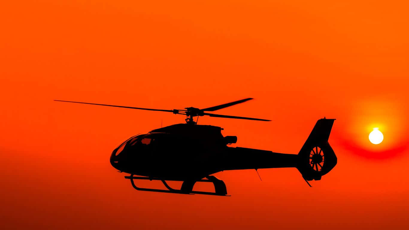 En helicopter flyver i den stribede himmel ved solnedgang.