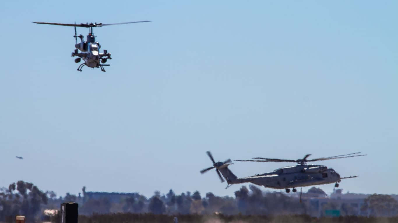 Et gruppe helikoptere flyver over et spektakulært landskab.