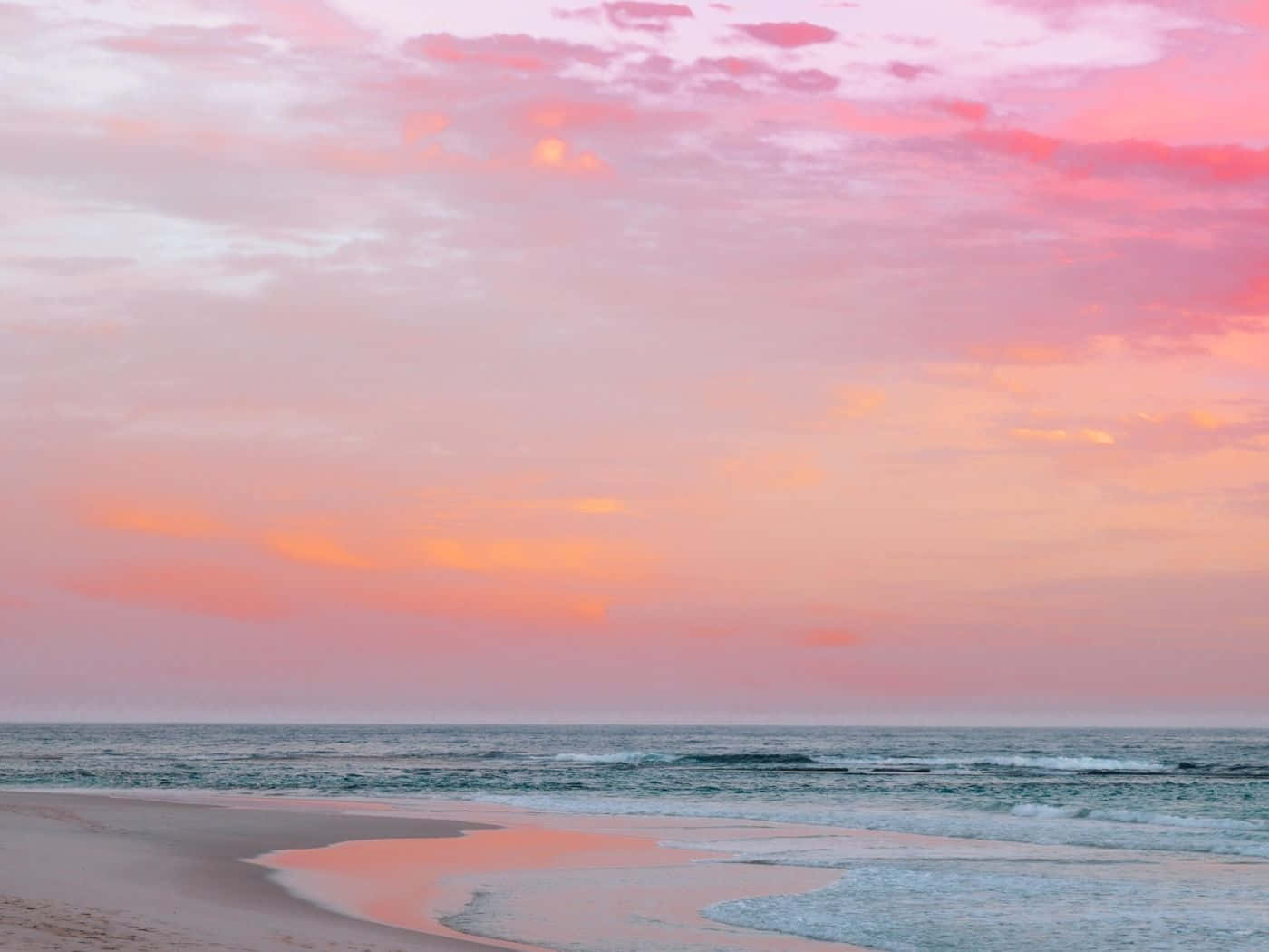 A Pink Sunset Over A Beach With Waves Wallpaper