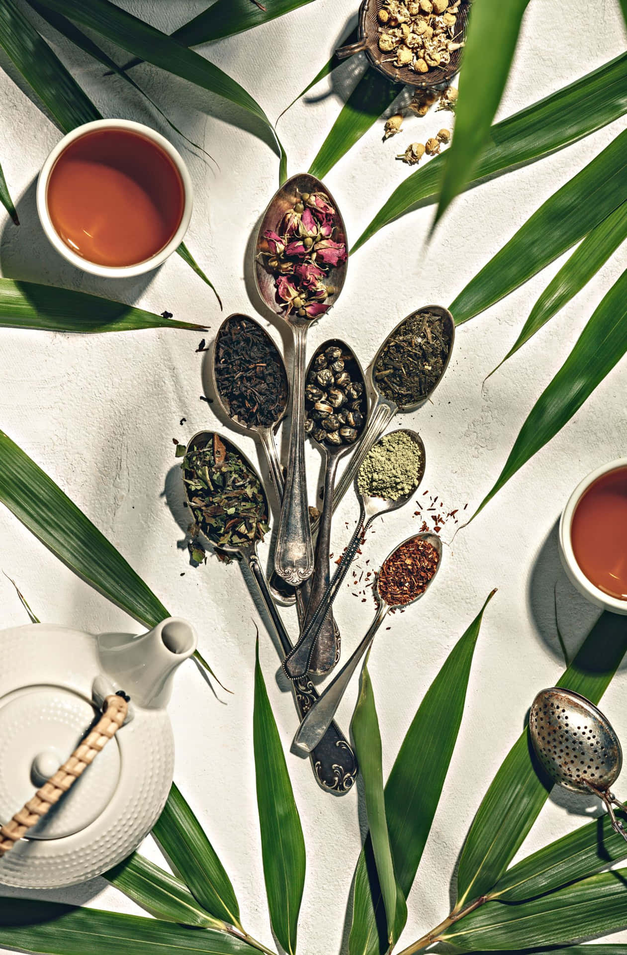 A Table With Tea Spoons And Tea Leaves Wallpaper