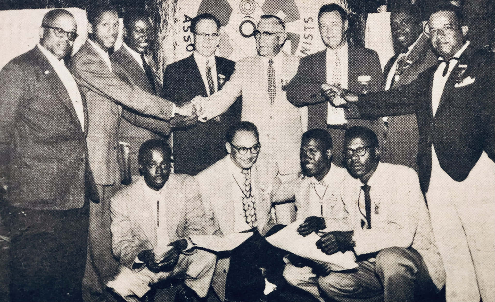 En gruppe mænd i jakkesæt og slips står sammen