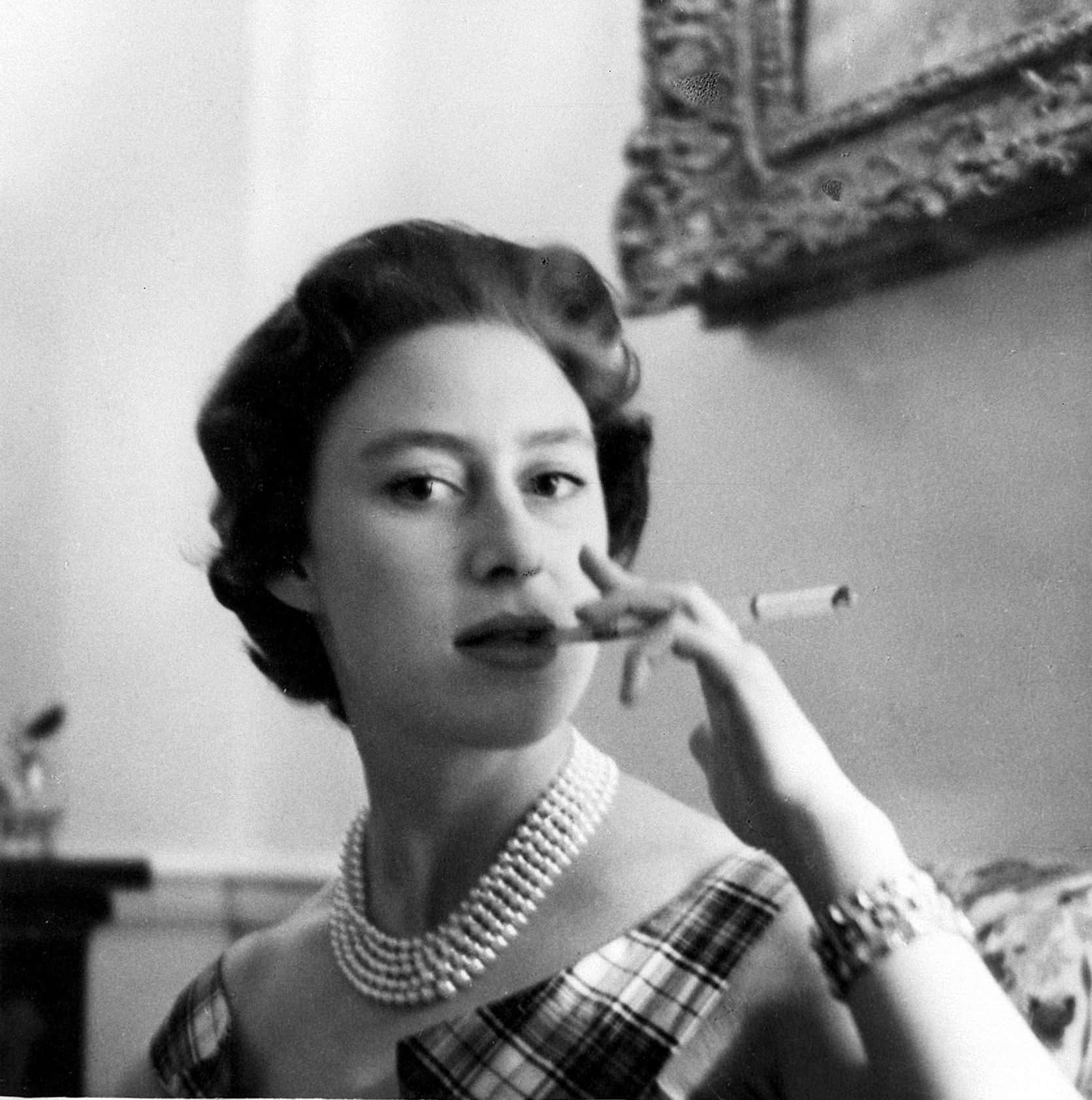 Elizabeth II ryger en cigaret i et rutet kjole.