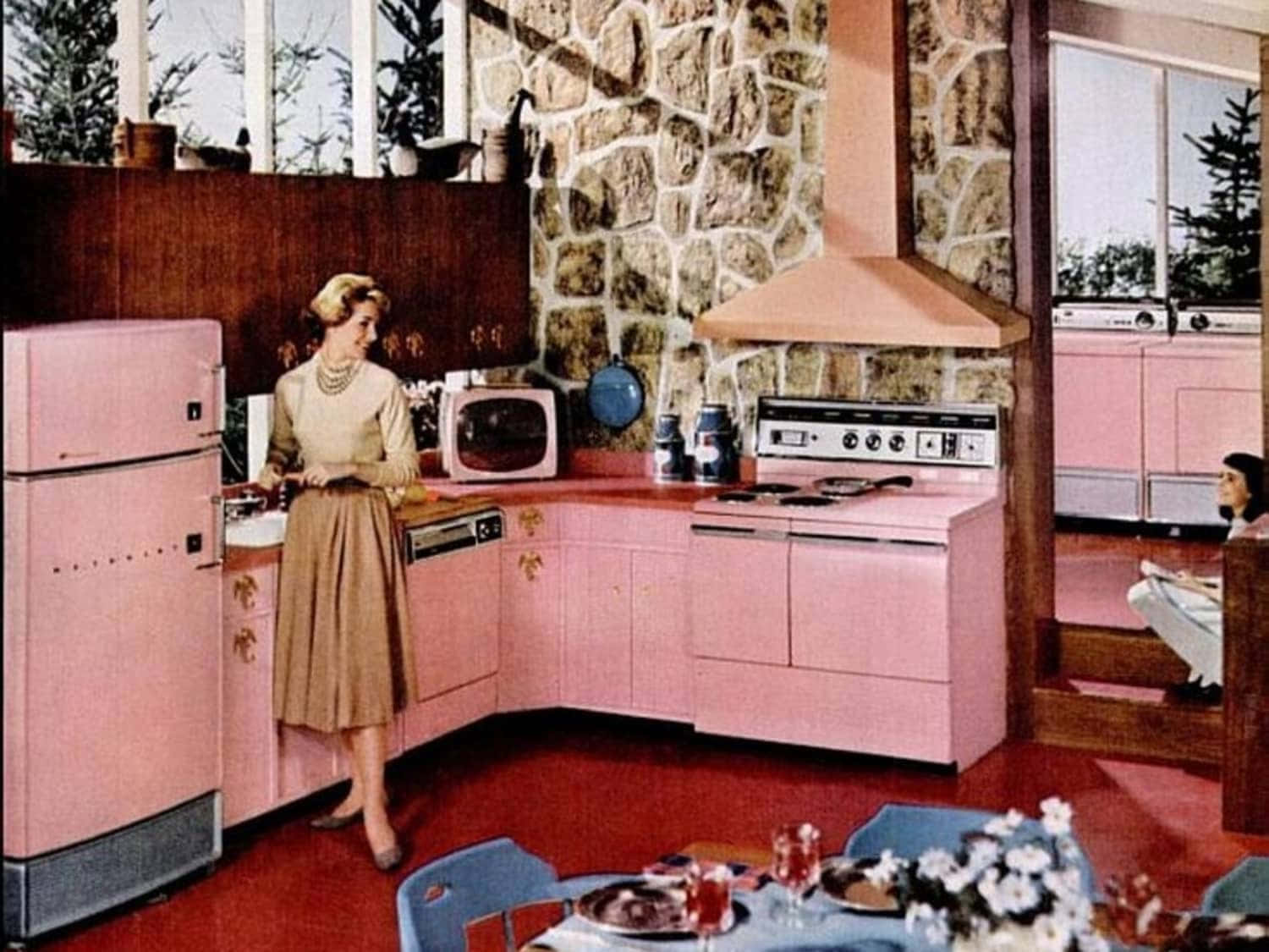 A Woman Is Standing In A Kitchen With Pink Appliances