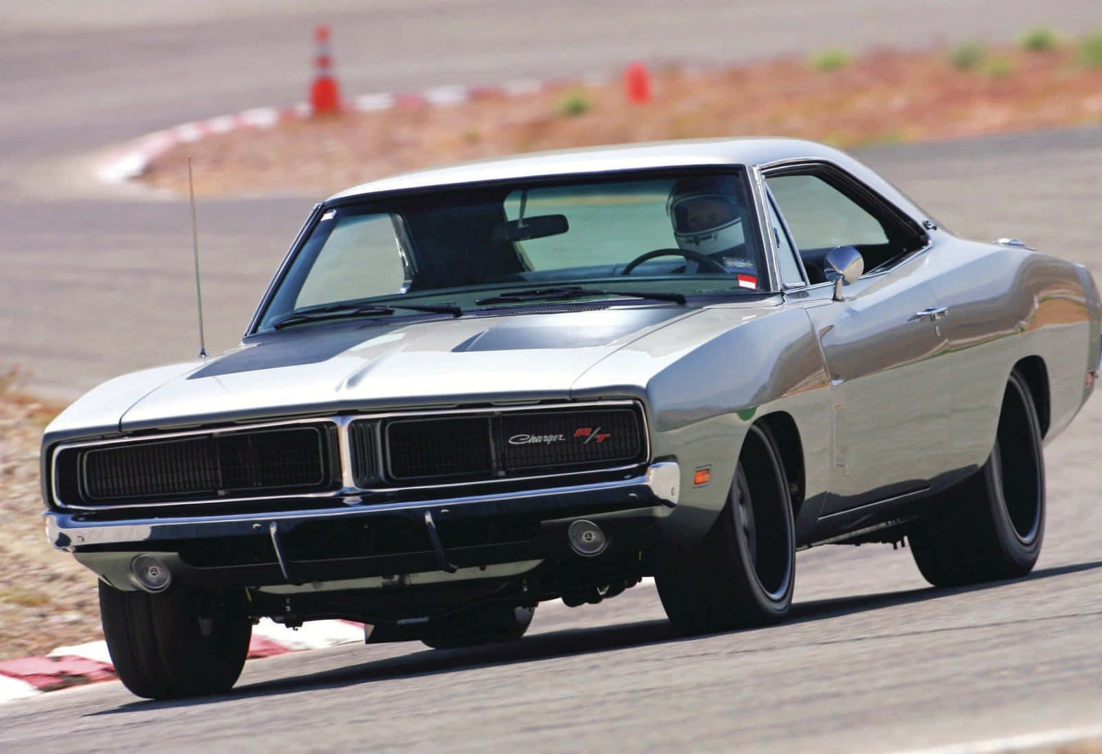 A Silver Muscle Car Driving On A Track