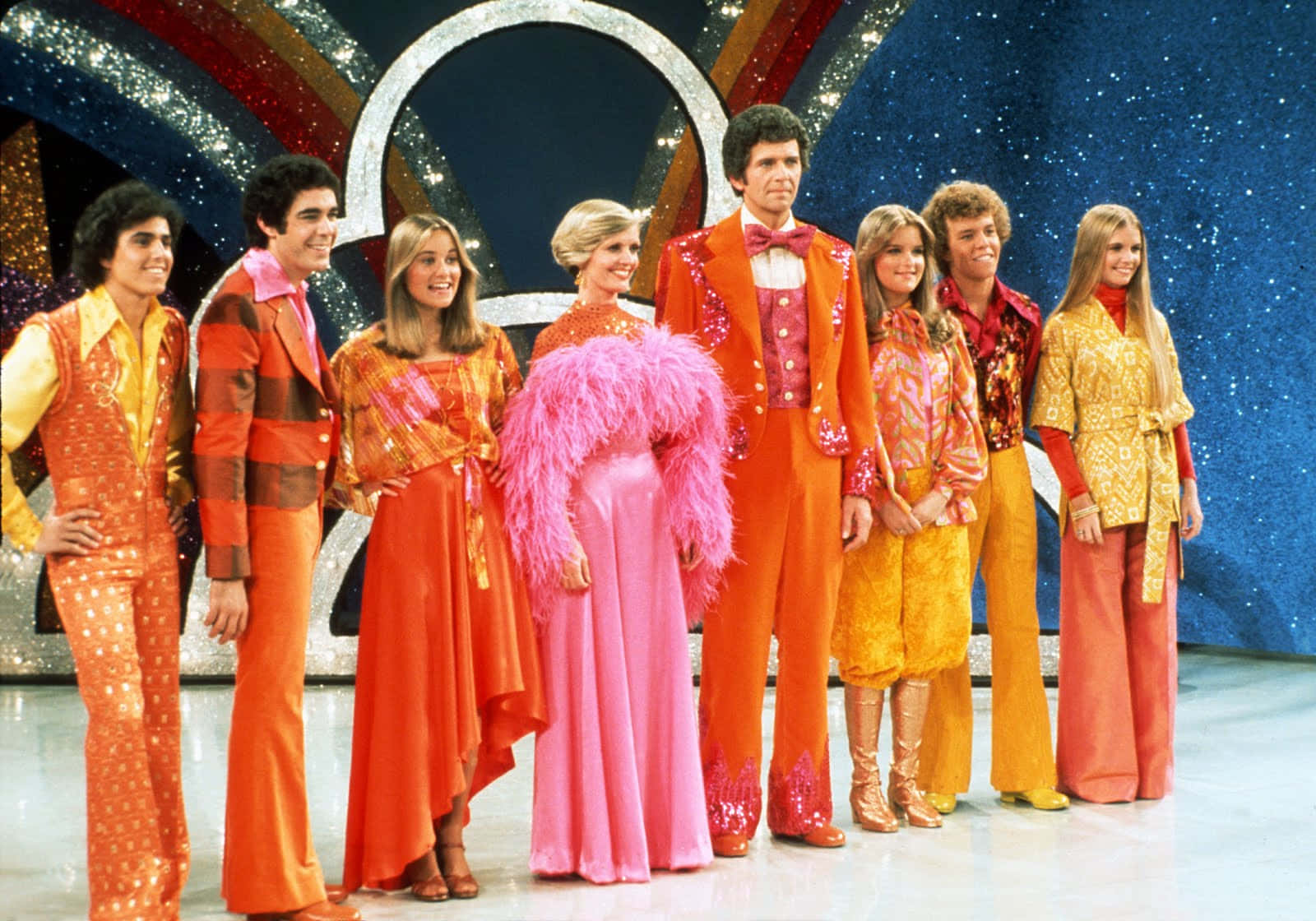 A Group Of People In Orange Costumes Standing On Stage