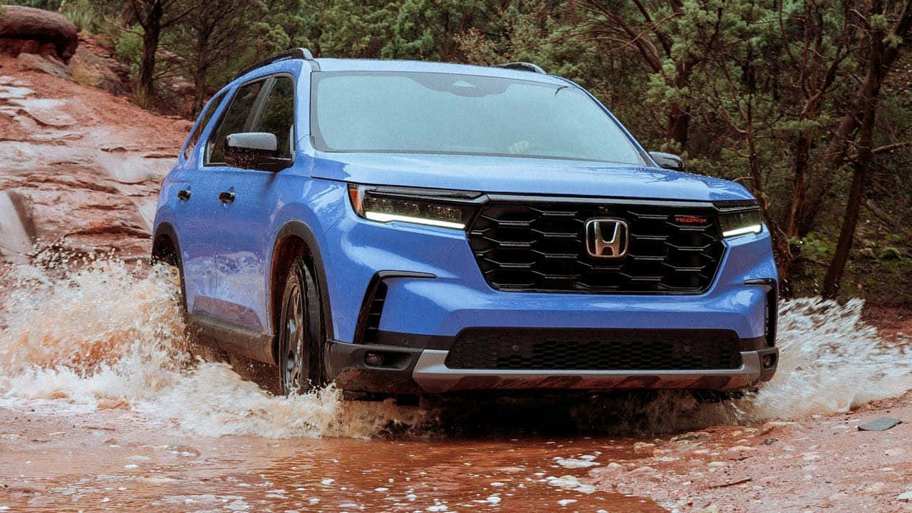 The Blue 2020 Honda Pilot Is Driving Through A Muddy Area