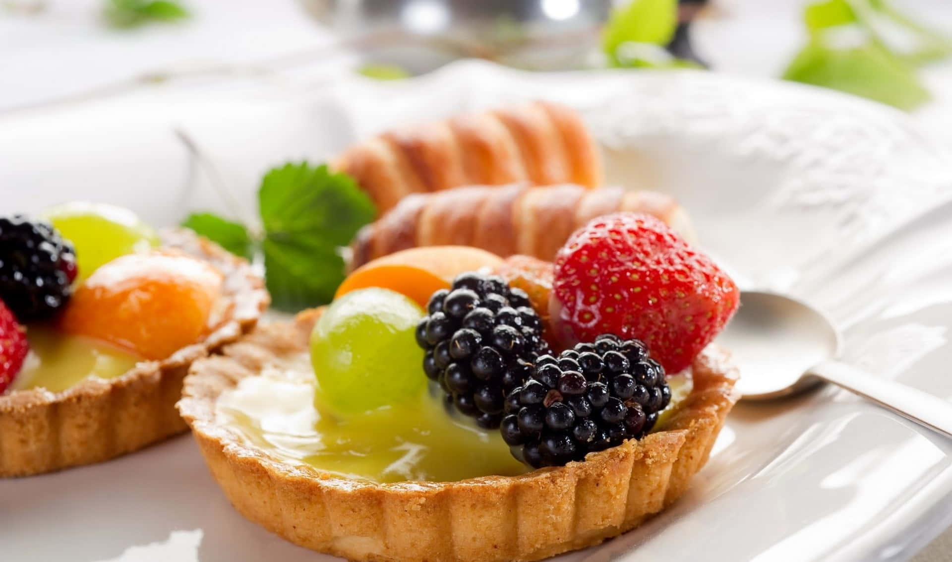 Two Fruit Tarts On A Plate With A Spoon