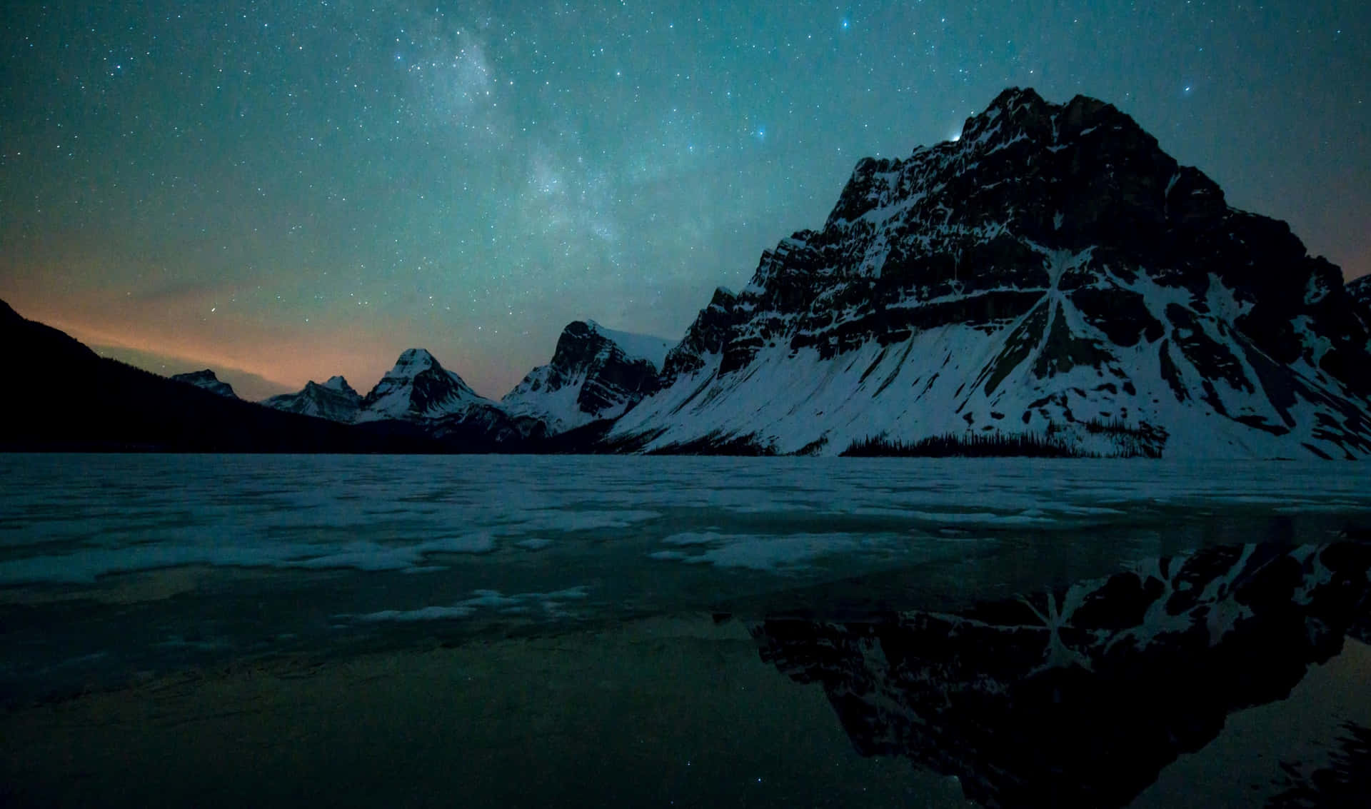 a mountain range is reflected in a lake with stars