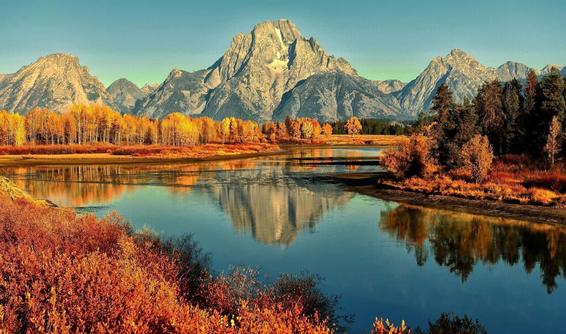a river reflects the mountains in autumn