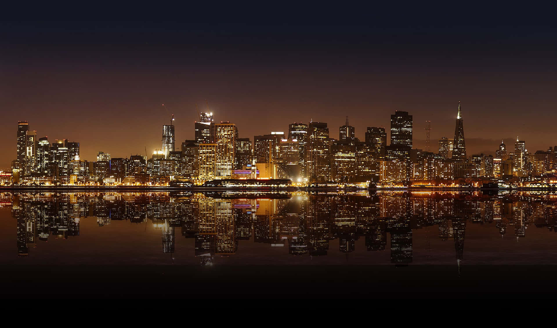 The iconic Bay Bridge and skyline of San Francisco, illuminated at night