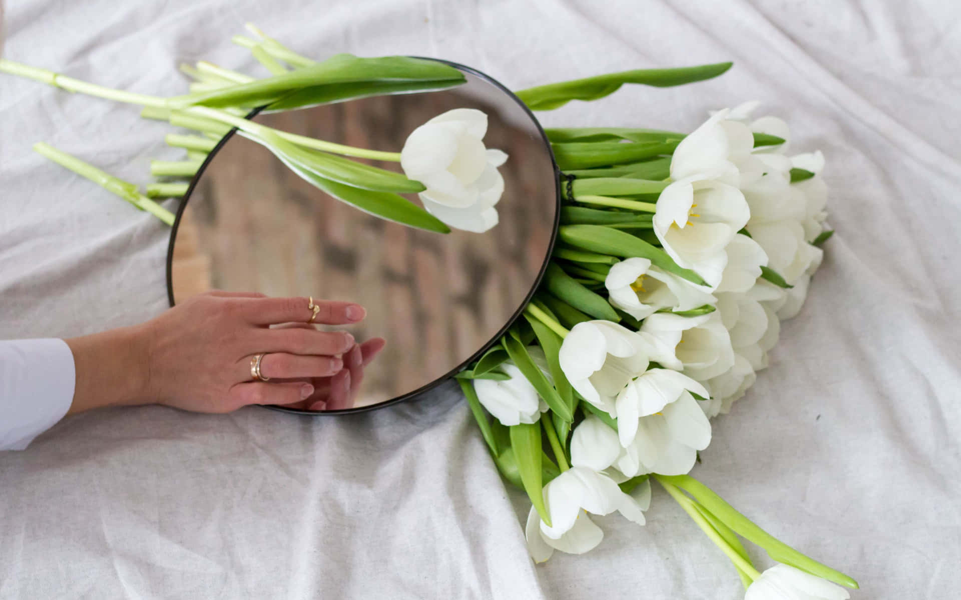 A Person Holding A Mirror Next To A Bouquet Of White Tulips Wallpaper