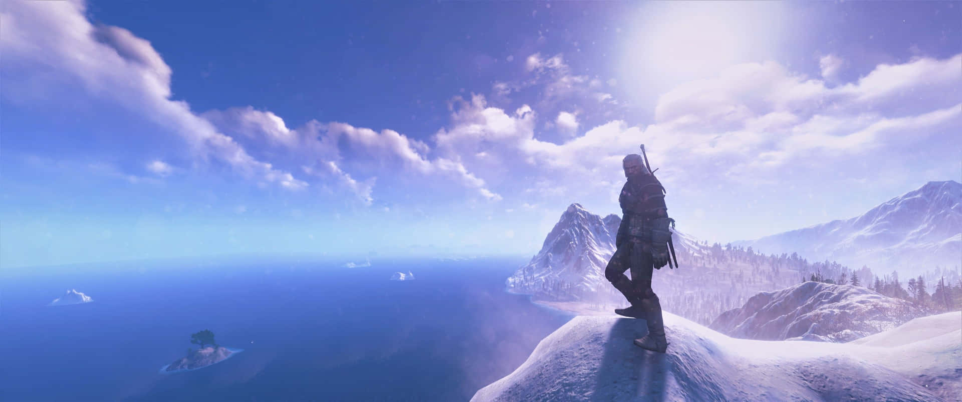 En mand står på toppen af et bjerg og ser på havet. Wallpaper