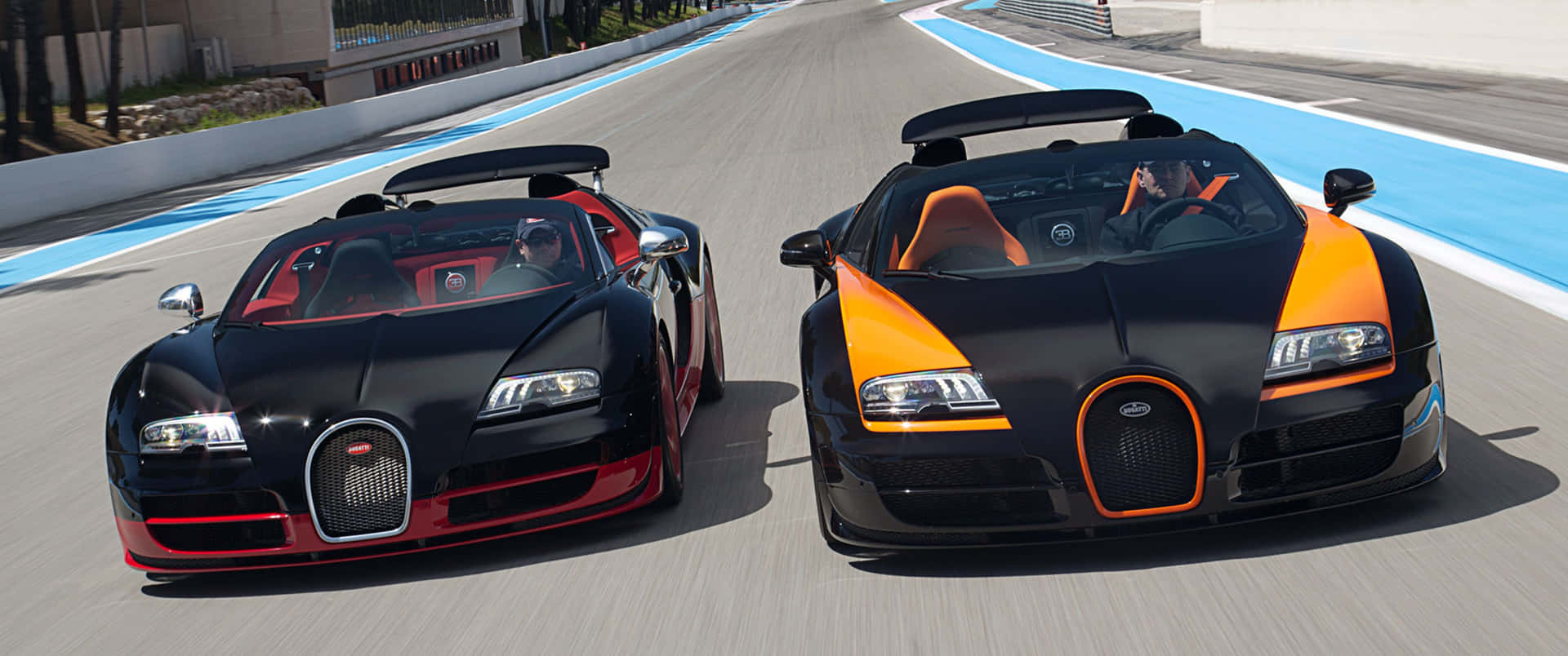 Two Bugatti Cars Are Driving Down A Track