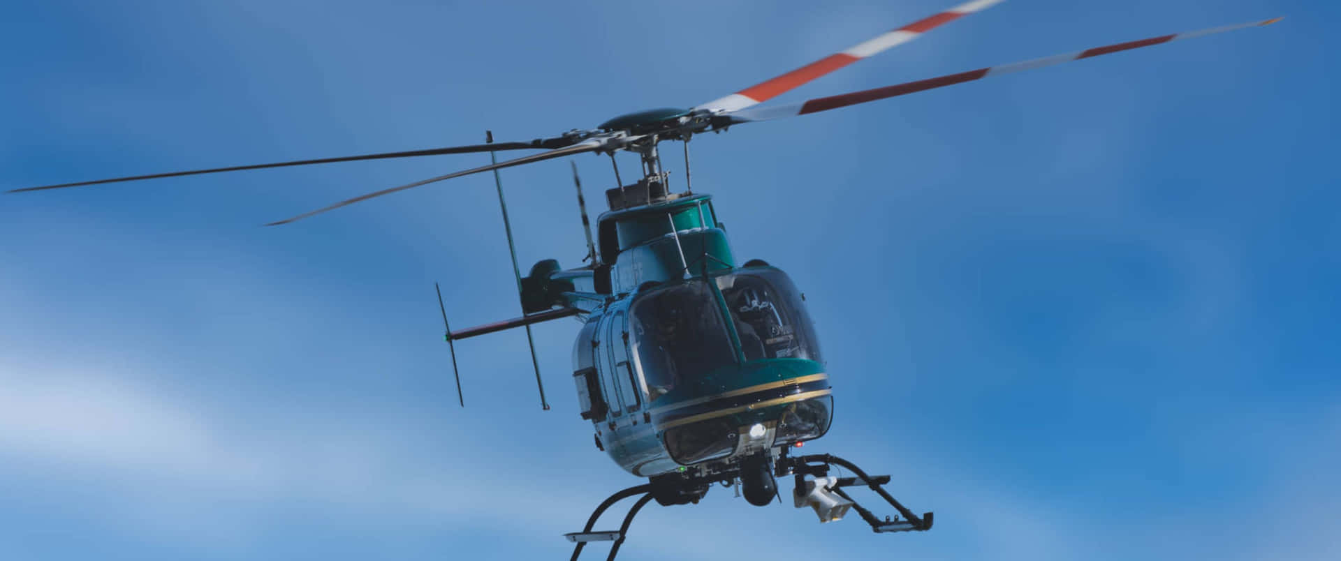 A Helicopter Flying In The Sky With A Green And Blue Color
