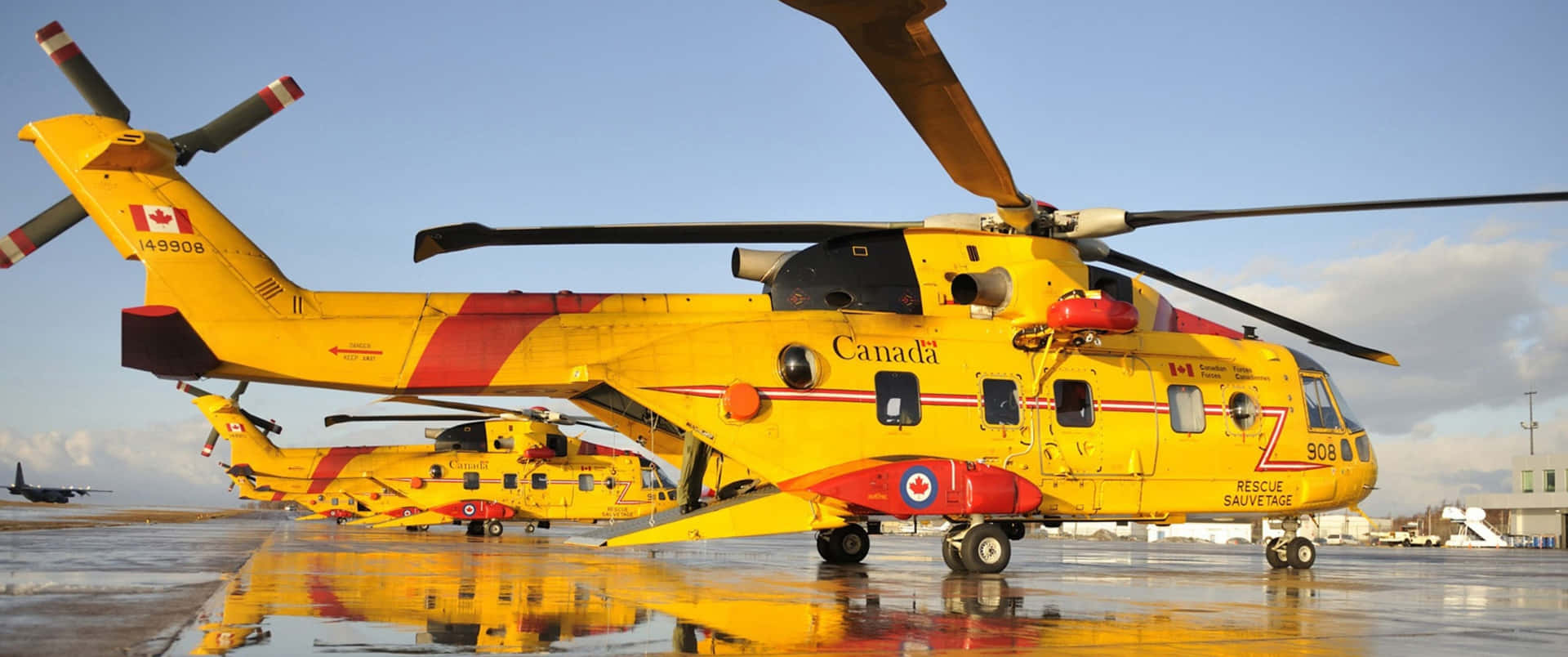 Two Yellow And Red Helicopters Parked On The Tarmac