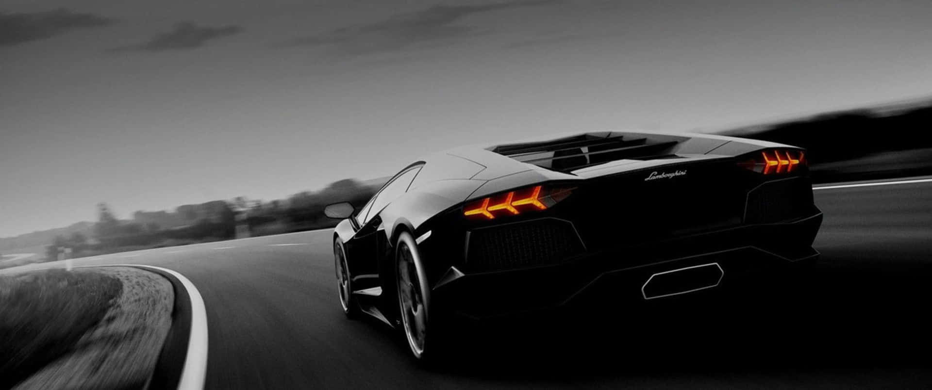 A Black And White Image Of A Sports Car Driving Down The Road