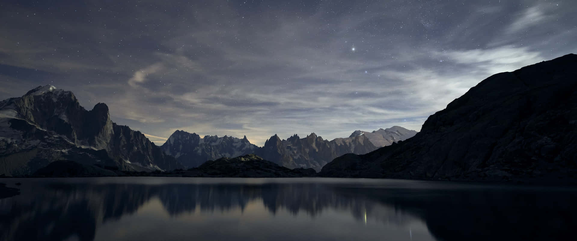 a mountain range is reflected in a lake at night