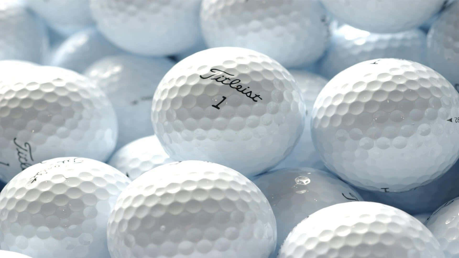 A Pile Of White Golf Balls With The Word Titleist Wallpaper