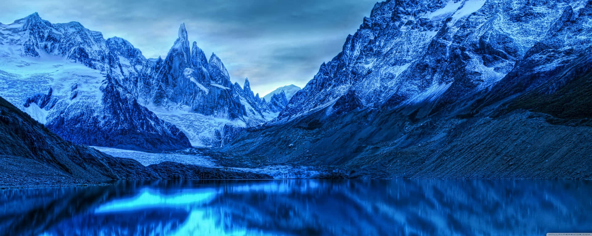 A Blue Mountain Range With A Lake In The Background Wallpaper