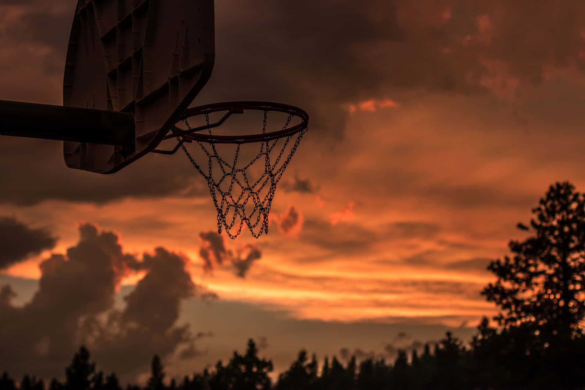 A Basketball Hoop With A Sunset Sky Behind It