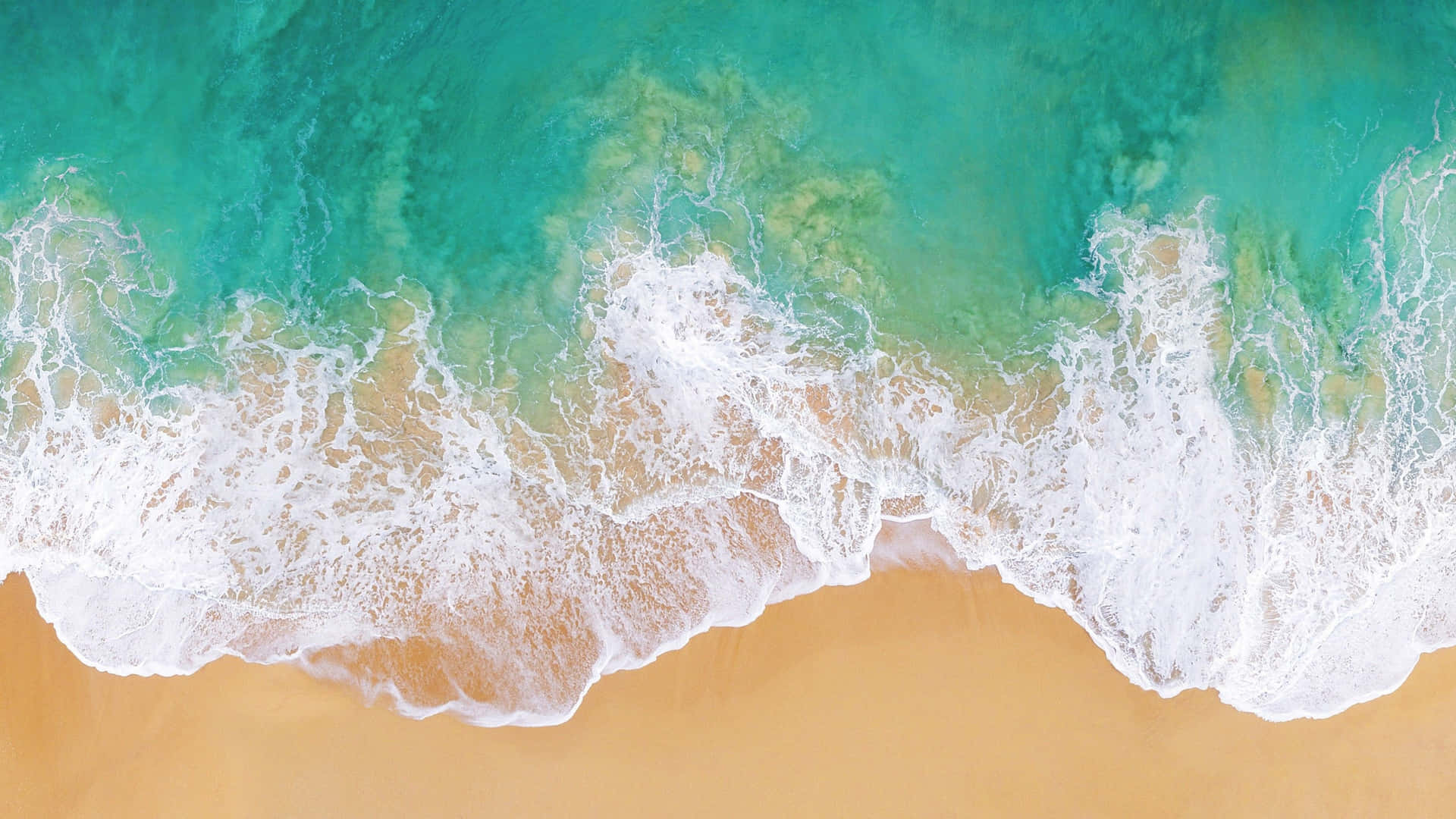 An Aerial View Of A Beach With Waves