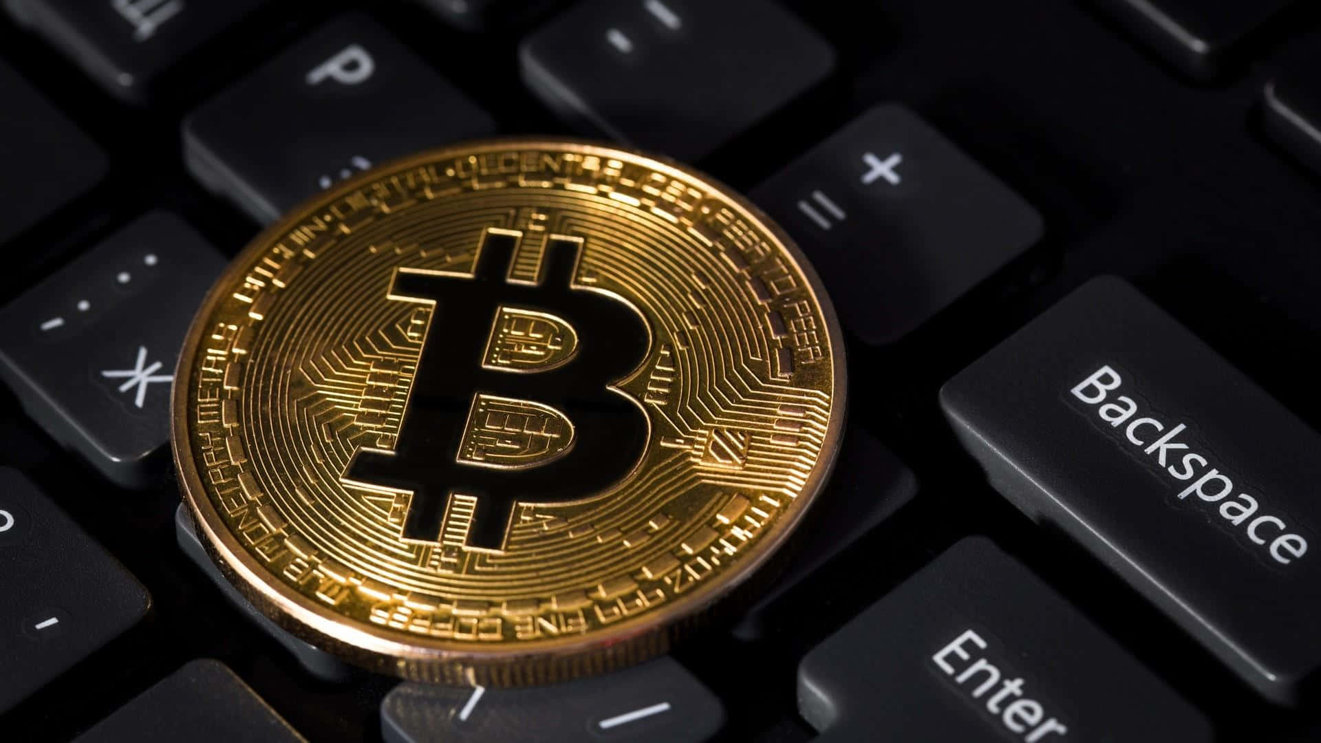 En bitcoin sidder på toppen af et tastatur Wallpaper
