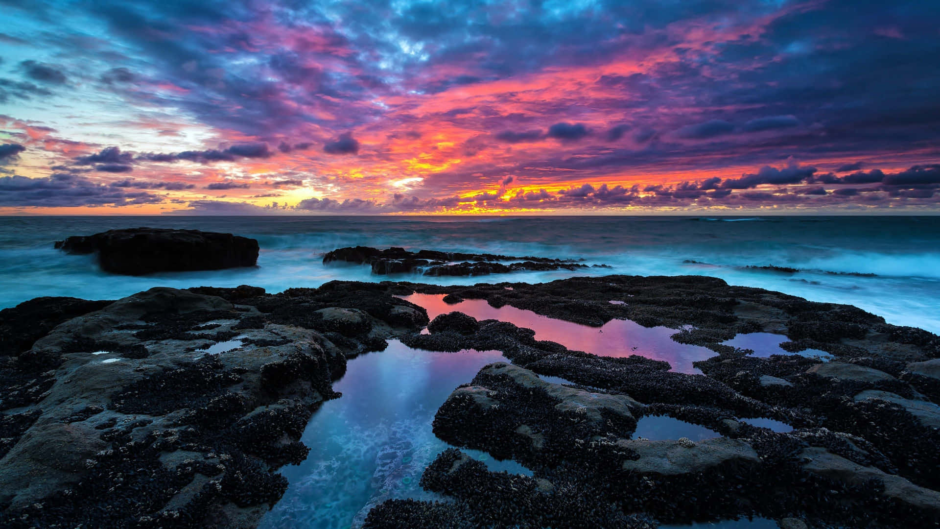A Colorful Sunset Over Rocks And Water