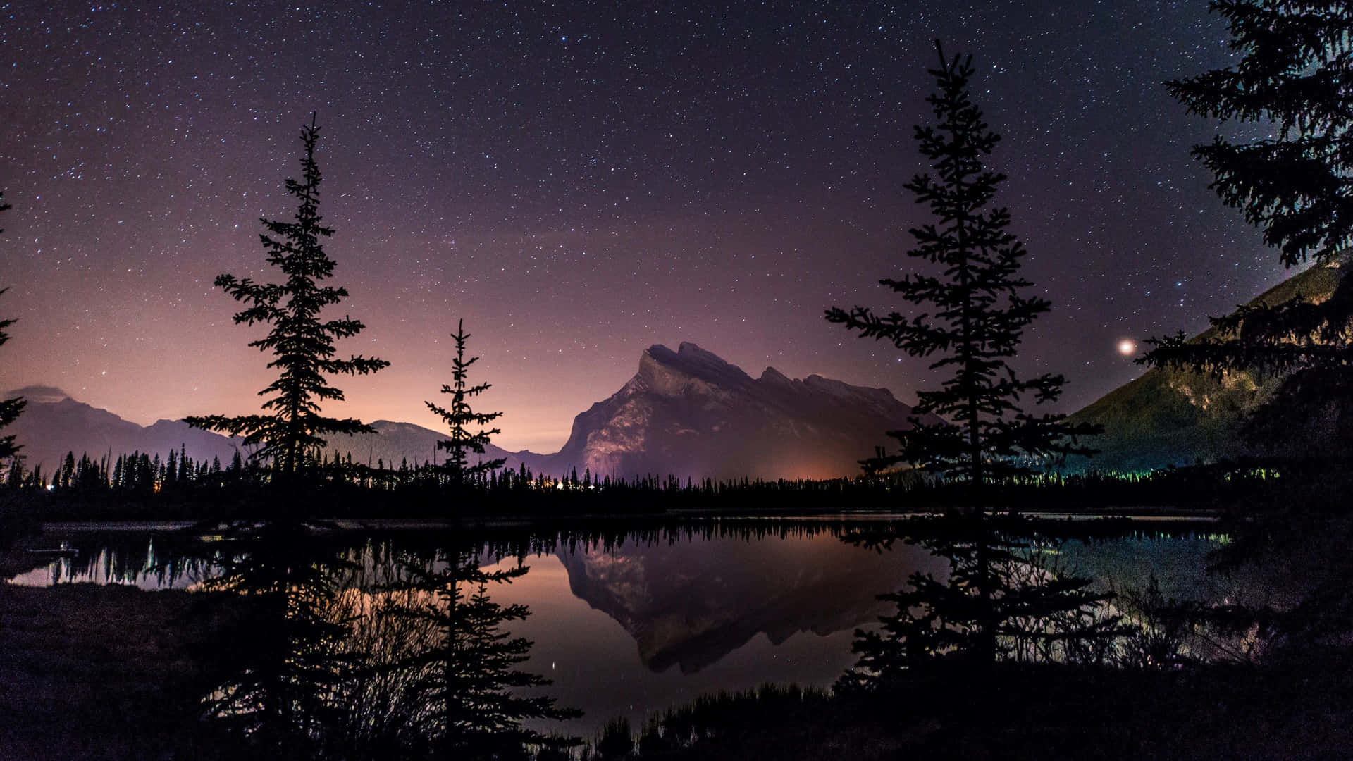 A Mountain Range Is Reflected In A Lake At Night